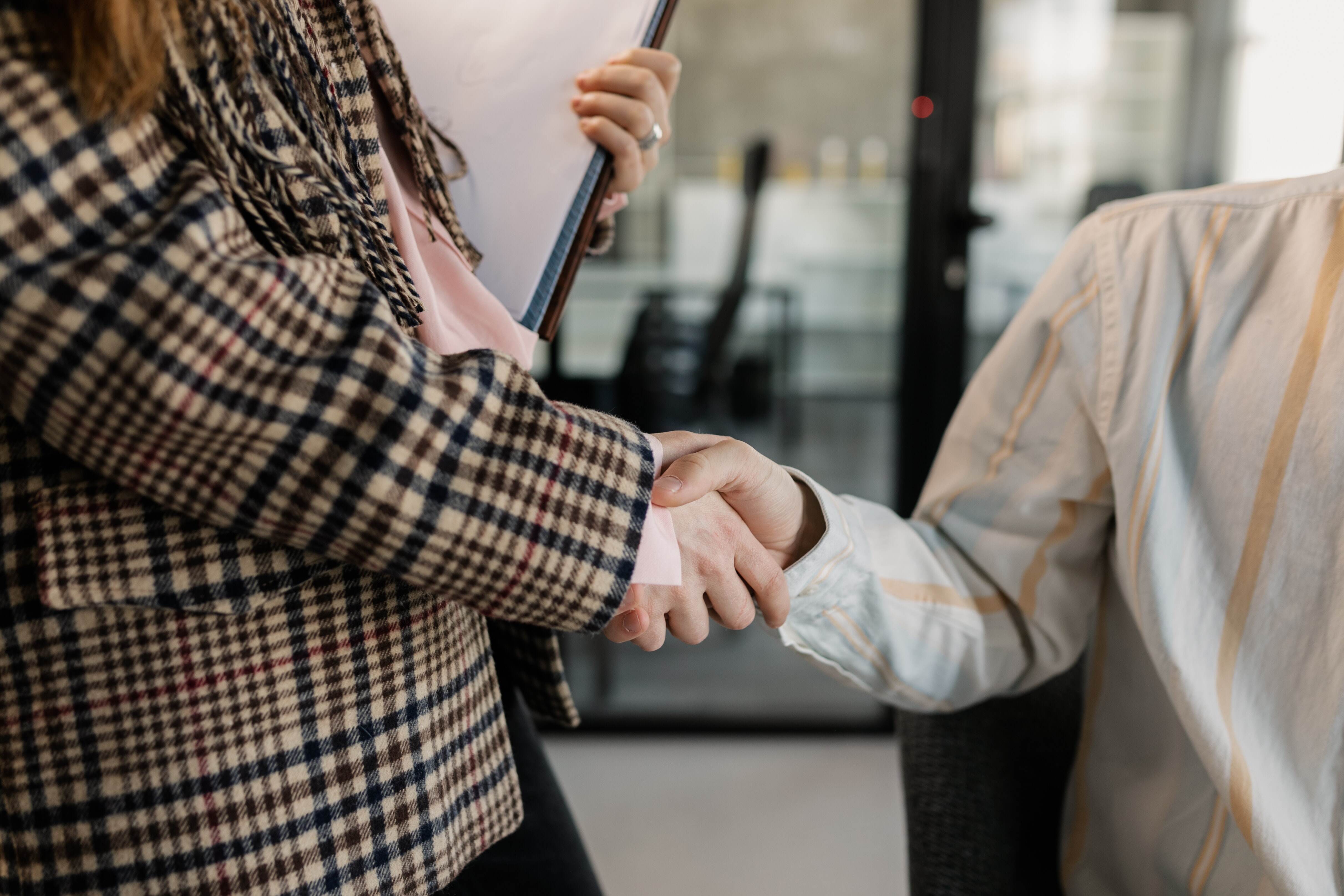 two office employees shaking hands after closing a deal