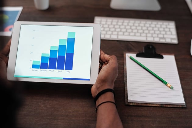 person at desk with ipad looking at chart showing revenue increasing month over month