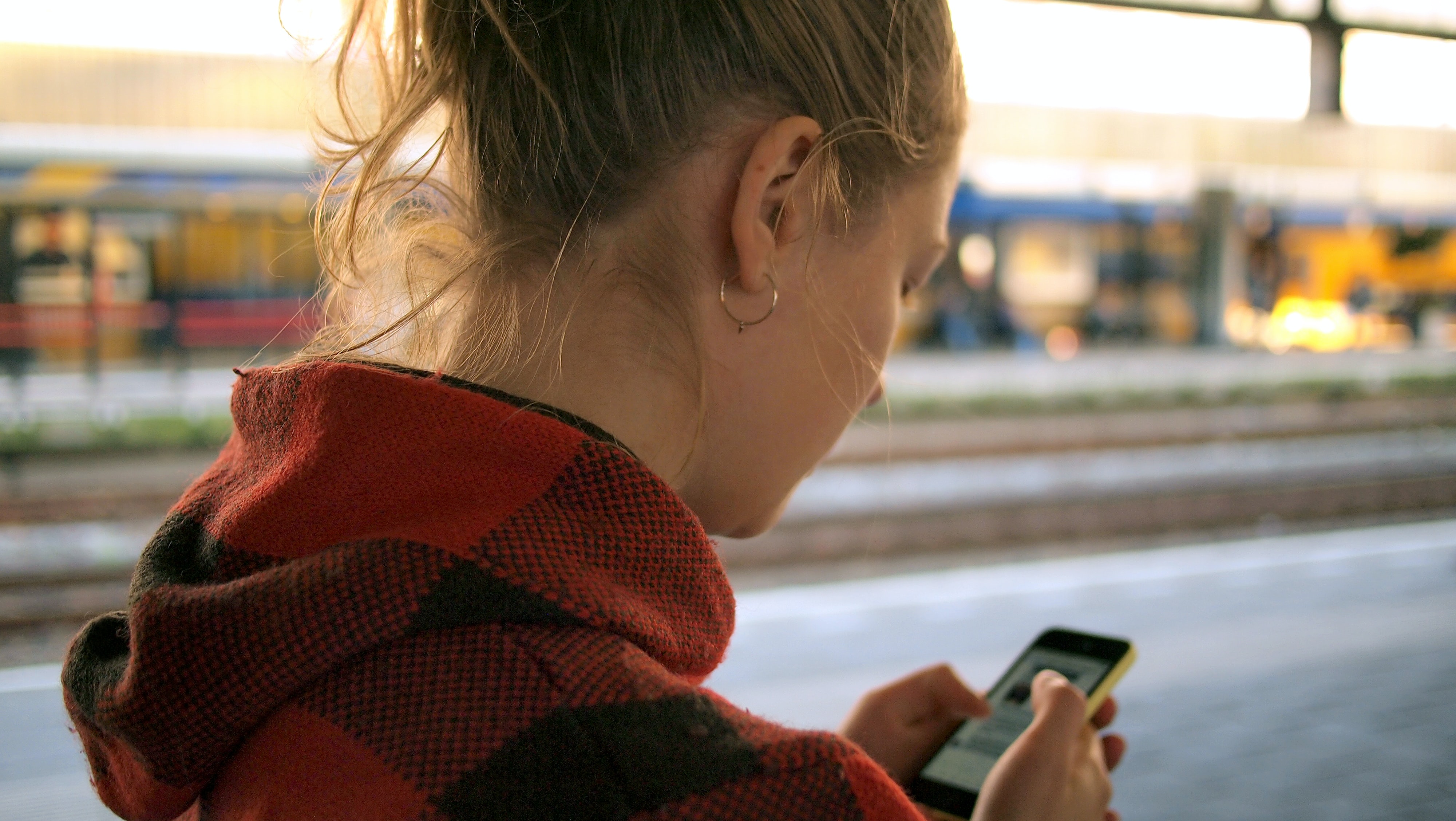 woman-at-train-station-checking-her-text-messages