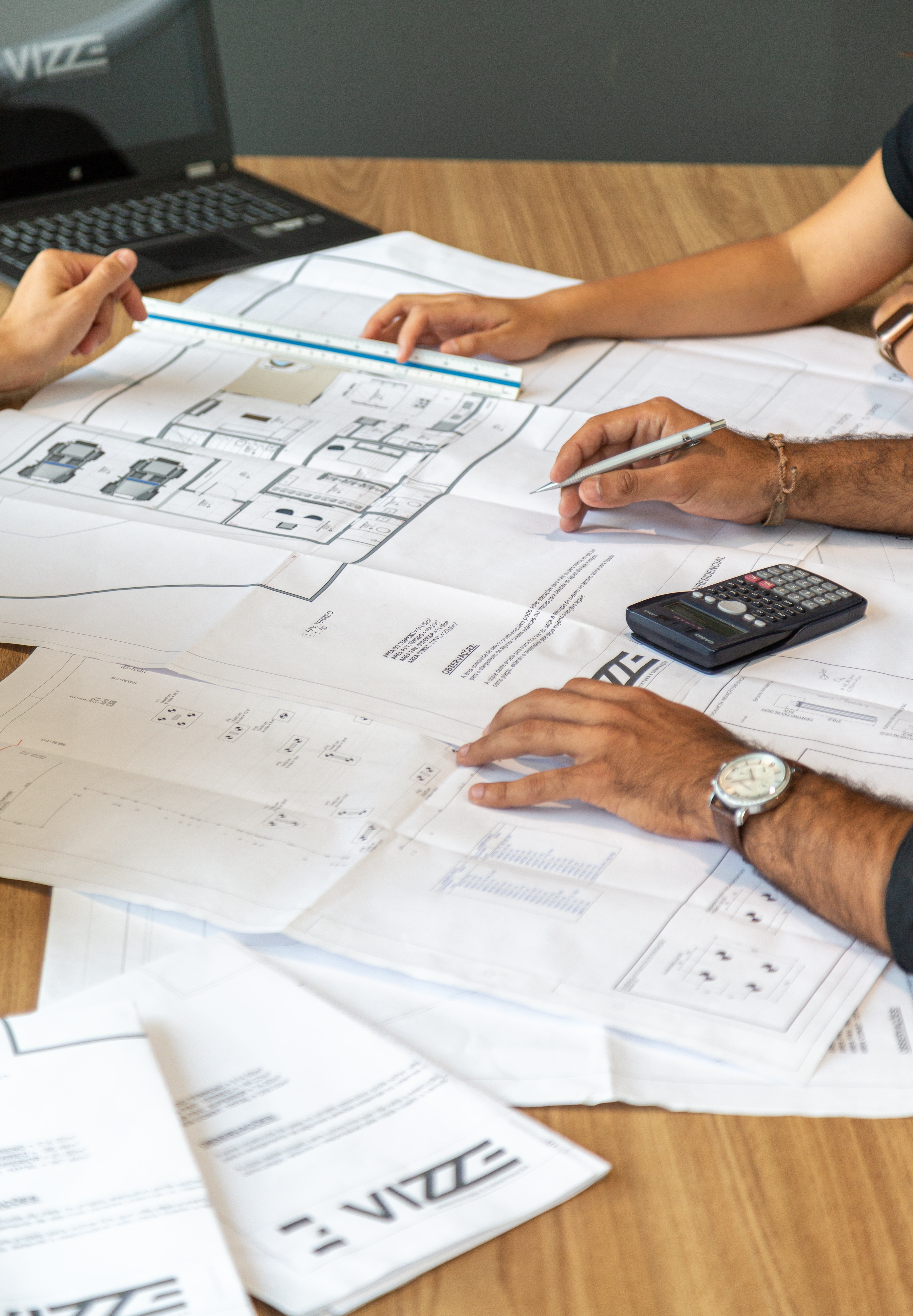 people-sitting-around-a-table-looking-at-building-schematics